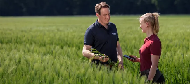 Ein BASF Berater unterhält sich mit einer Frau auf einem Feld.
