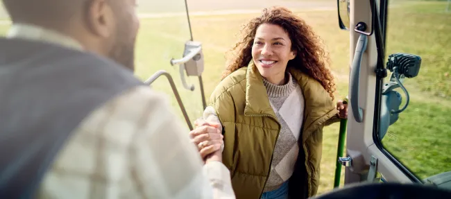 Ein Mann reicht einer Frau eine Hand aus seinem Traktor