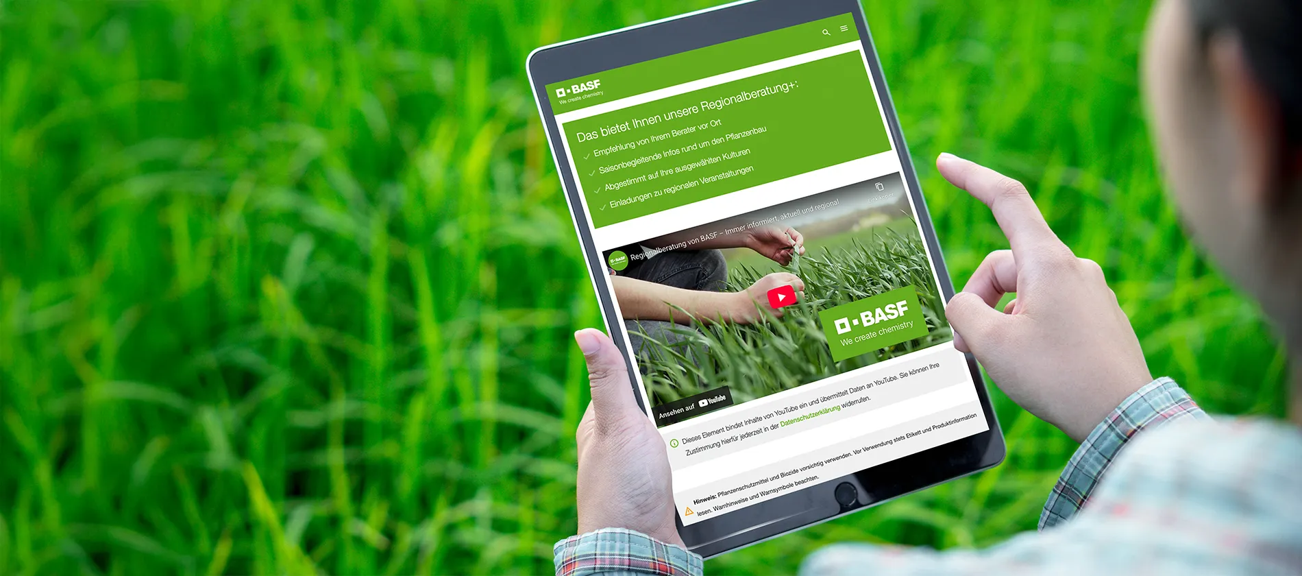 Ein Mann hat ein Tablet mit Regionalberatung+ in der Hand auf einem Feld.