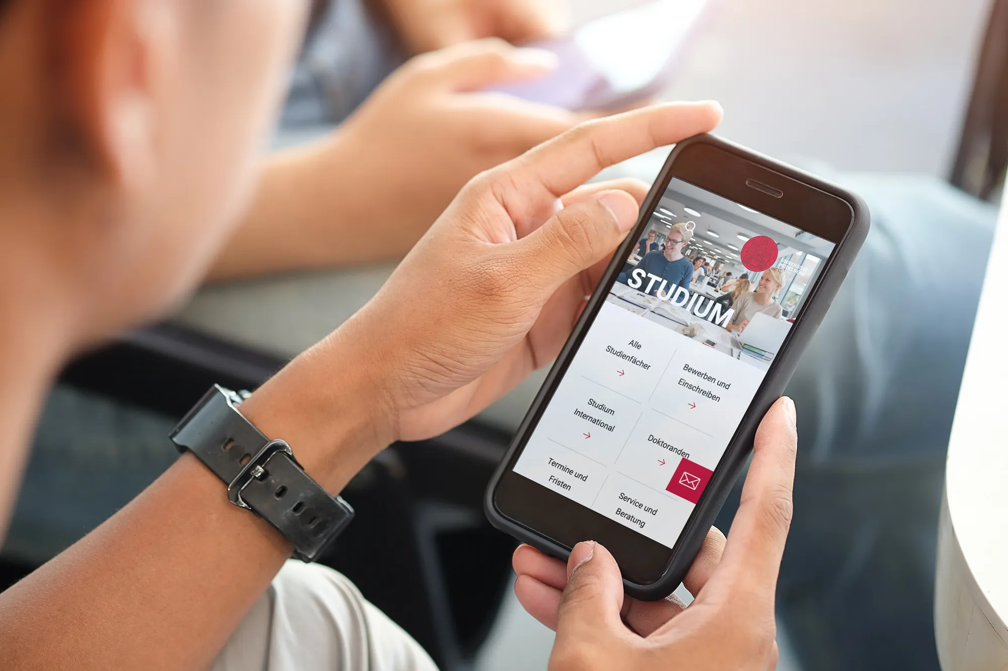 Ein Mann schaut sich die Website der Uni Heidelberg auf einem Smartphone an.