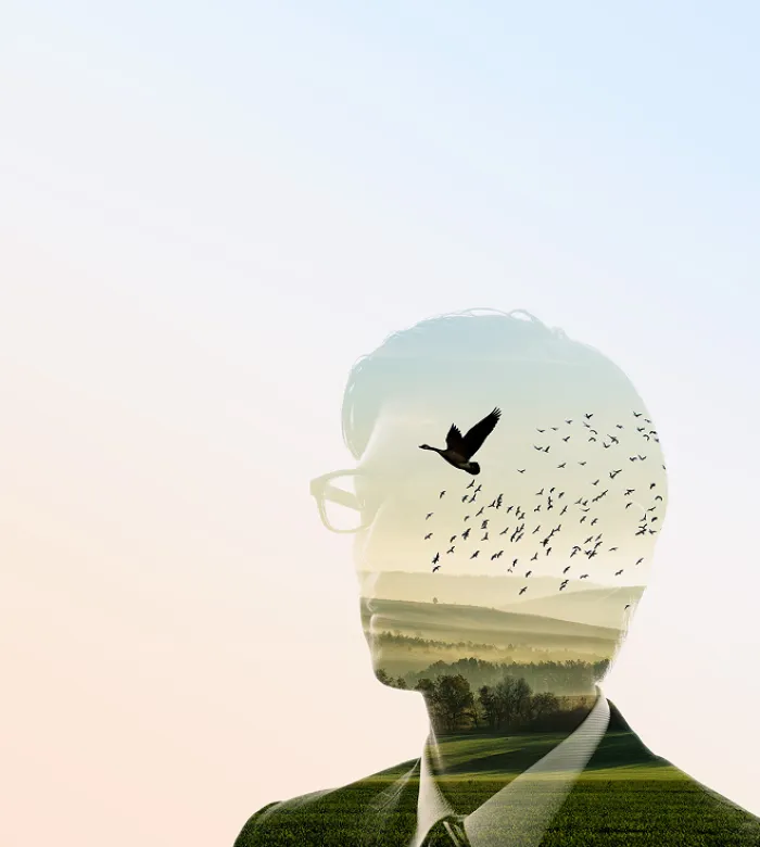 Eine Doppelbelichtung eines Manns und eines Vogelschwarms