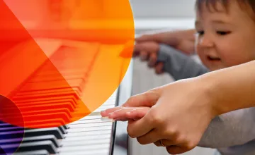 Ein Kind versucht auf einem Klavier zu spielen.