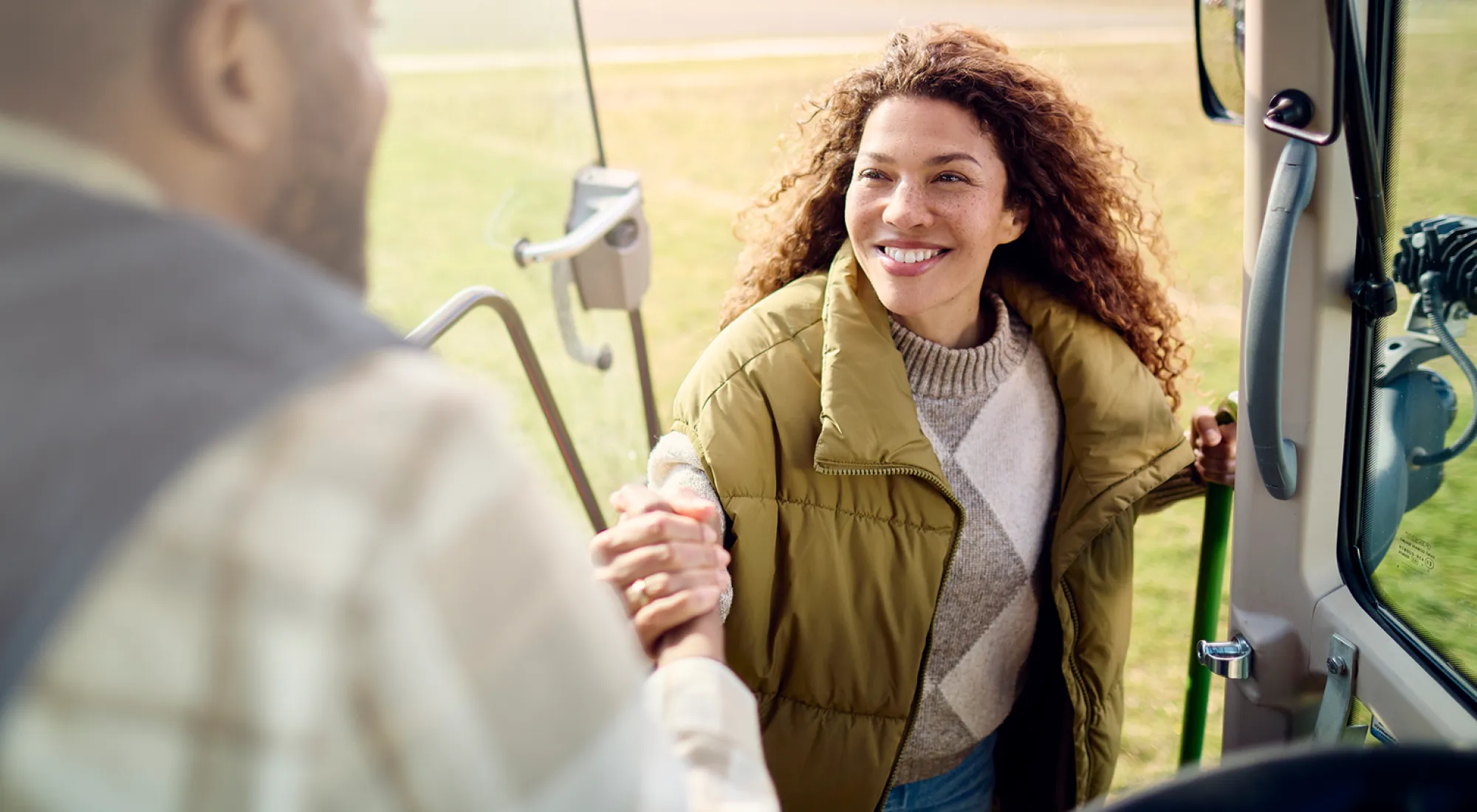 Ein Mann reicht einer Frau eine Hand aus seinem Traktor